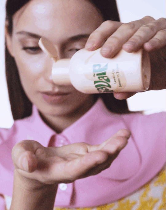 Close-up of a woman in a pink blouse pouring Savaip Serum-in-Toner hydrating toner. 